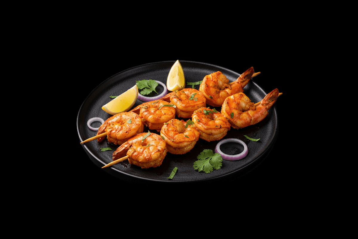 Komla Jingha — King prawns stir-fried in a Bhoona sauce, flavoured with citrus fruits, served inside a fresh orange shell, GB