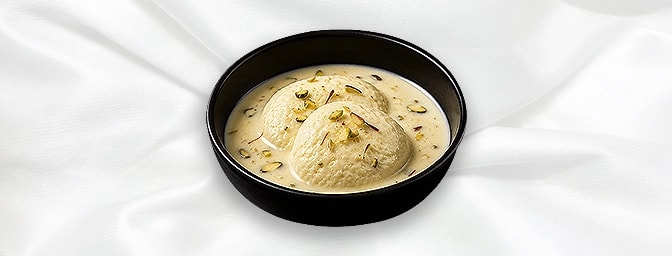 Rasmalai — Fresh milk cake dipped in a creamy sauce flavoured with saffron and cardamom, dressed with slivers of almond, GB C