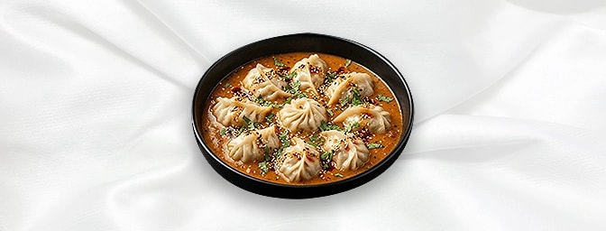 Jhol Momo — Steamed momo bathed in warm or cold spicy and tangy sesame-tomato broth, a flavourful street-food style from Kath