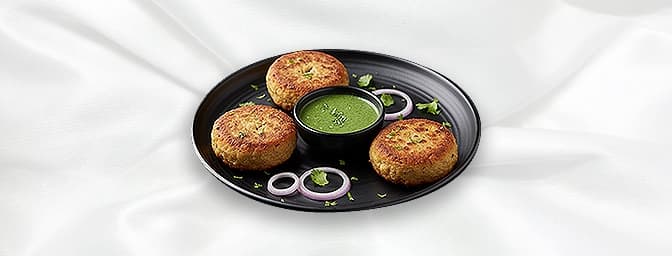 Shami Kebab — Pan Fried patty, made with minced lamb, a smooth lentil paste, then coated with eggs to lock in the flavour. Fr
