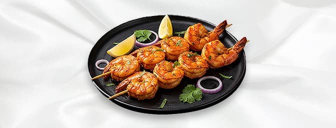 Tandoori King Prawn Shashlick — Shelled king prawns, delicately spiced and skewered with tomato, onions and garnished with fr