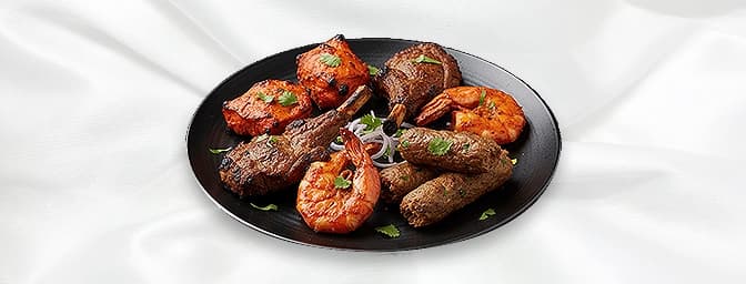 Tandoori Mix Platter — A selection of lamb, chicken tikka, seekh kebab, and tandoori chicken, served with naan bread, GB Cant