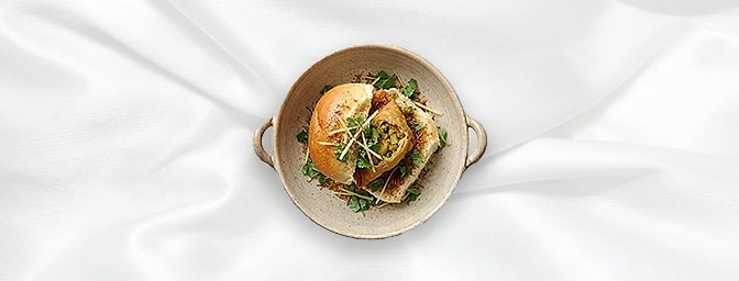 Bun Samosa — The ultimate comfort fusion: a crisp, savory vegetable samosa tucked inside a soft bun. Drizzled with signature