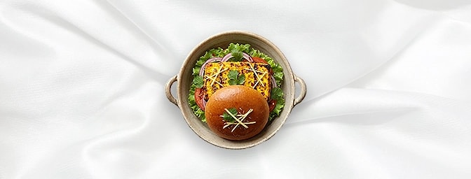 Paneer Tikka Burger — A vegetarian delight featuring a thick slab of grilled paneer, marinated in yogurt and spices. Served w