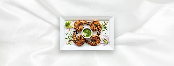 Tandoori Jingha — The ultimate seafood luxury. Magnificent jumbo prawns are marinated in a vibrant bouquet of fresh herbs and