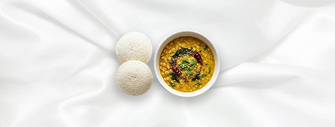 Tarka Dal with Idli — Experience South Indian comfort at its finest. Soft, pillowy steamed rice cakes served alongside our si