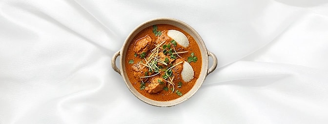 Butter Chicken with Idli — Our iconic barbecued chicken, bathed in a rich, buttery tomato cream sauce. We've swapped the trad